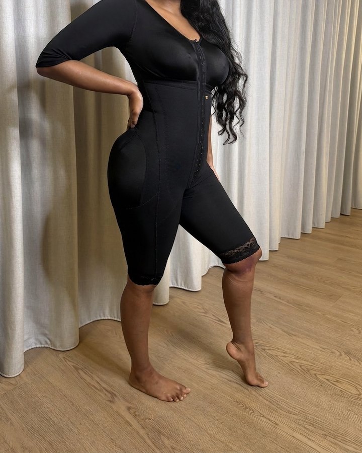 Client wearing a black full-body stage-2 compression faja with sleeves, front hook-and-eye closure and lace-trim legs, fitted at Lymphyx